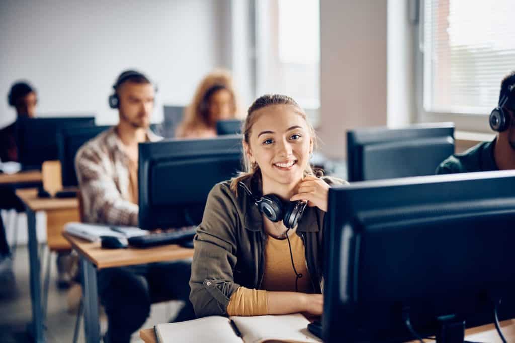 Female student in a computer lab classroom with headphones on